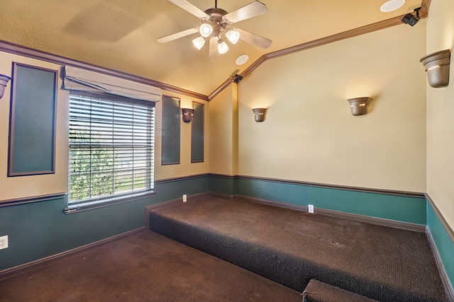 cinema with ceiling fan, dark carpet, ornamental molding, and vaulted ceiling