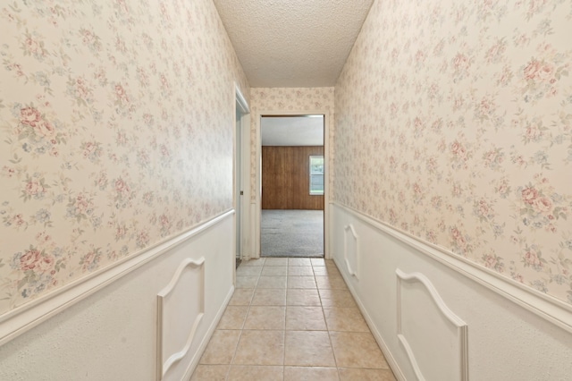 hall featuring light tile patterned flooring and a textured ceiling