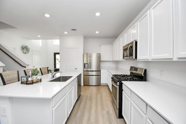 kitchen with a kitchen breakfast bar, sink, a center island with sink, and appliances with stainless steel finishes