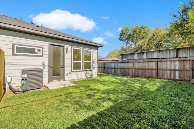 back of property featuring central AC unit and a yard