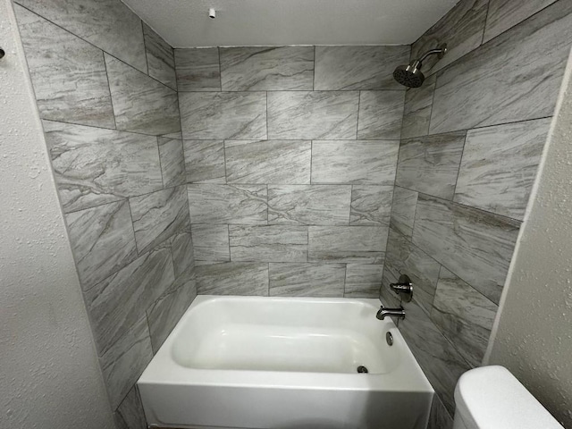 bathroom featuring toilet and tiled shower / bath