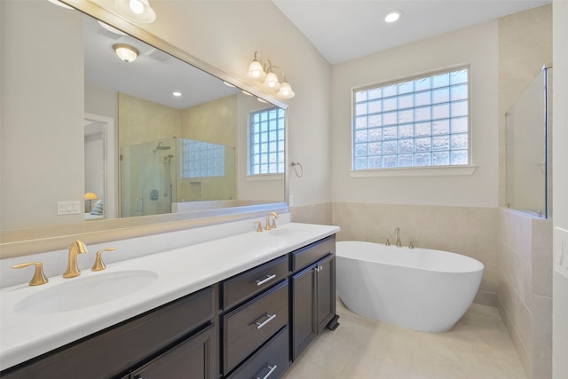 bathroom featuring tile patterned floors, vanity, shower with separate bathtub, and tile walls