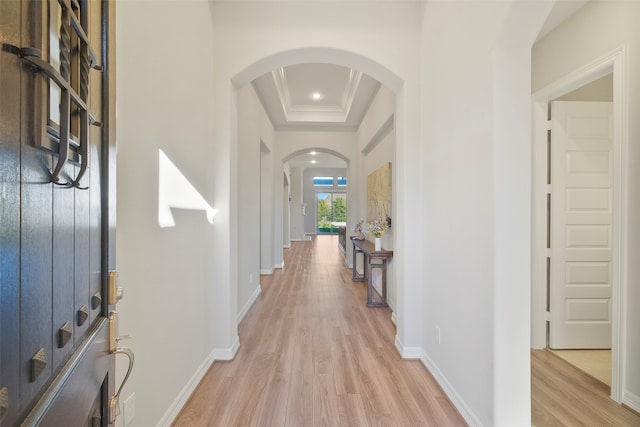 hall featuring light wood-type flooring and a raised ceiling