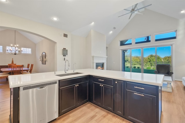 kitchen featuring light wood-type flooring, stainless steel dishwasher, ceiling fan with notable chandelier, sink, and high vaulted ceiling