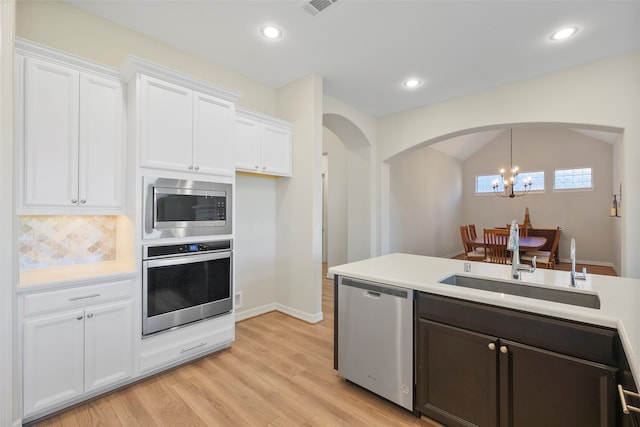 kitchen featuring an inviting chandelier, white cabinets, sink, decorative light fixtures, and stainless steel appliances