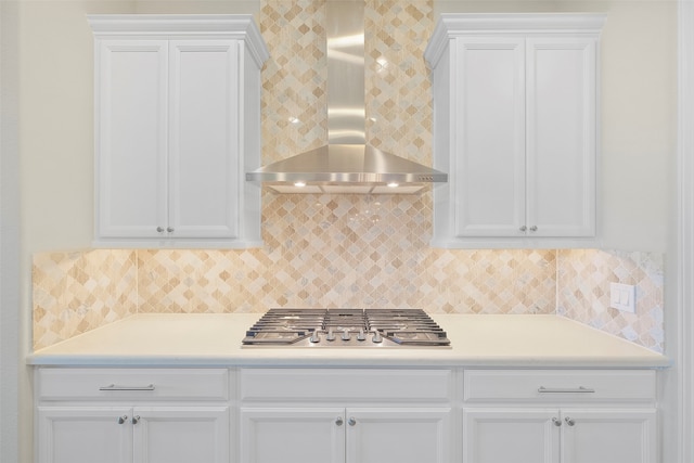 kitchen with backsplash, white cabinets, wall chimney exhaust hood, and stainless steel gas stovetop