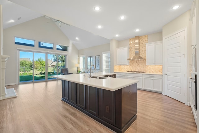 kitchen with a center island with sink, wall chimney exhaust hood, light hardwood / wood-style floors, and sink