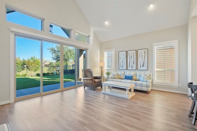 living room featuring high vaulted ceiling and light wood-type flooring