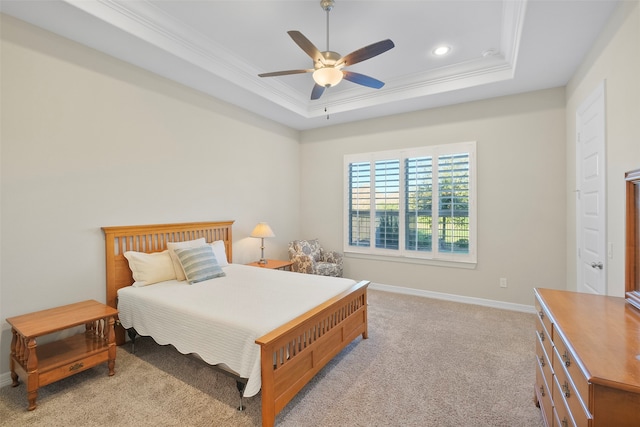 carpeted bedroom with a tray ceiling, ceiling fan, and crown molding