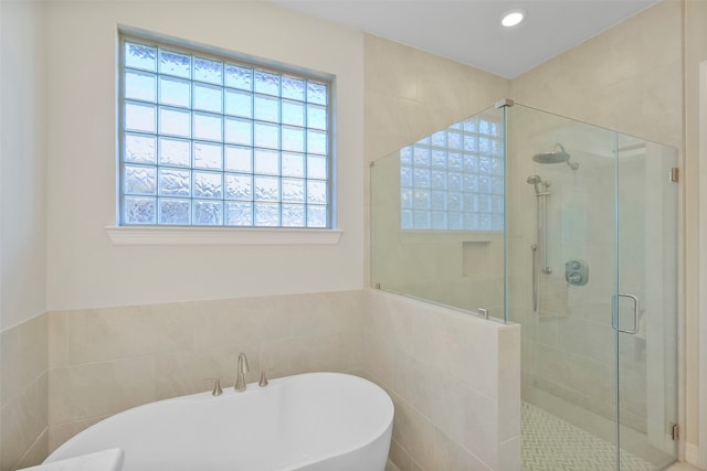 bathroom featuring tile walls and shower with separate bathtub