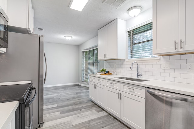 kitchen featuring sink, white cabinets, a healthy amount of sunlight, and appliances with stainless steel finishes