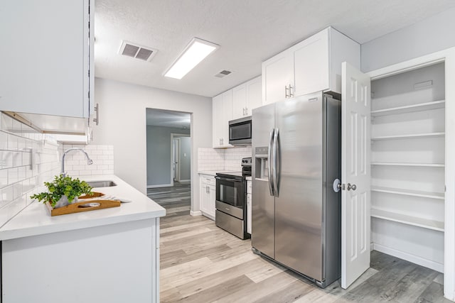 kitchen with tasteful backsplash, white cabinetry, sink, and stainless steel appliances