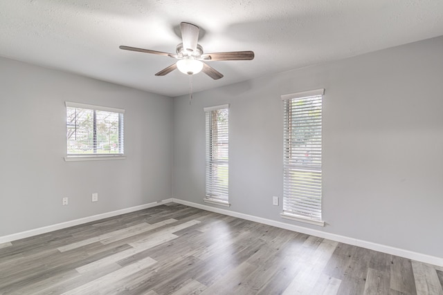 empty room with ceiling fan, a textured ceiling, and light hardwood / wood-style flooring