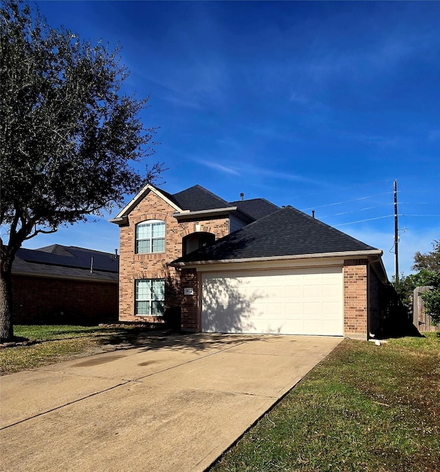 traditional-style home with a shingled roof, brick siding, driveway, and an attached garage