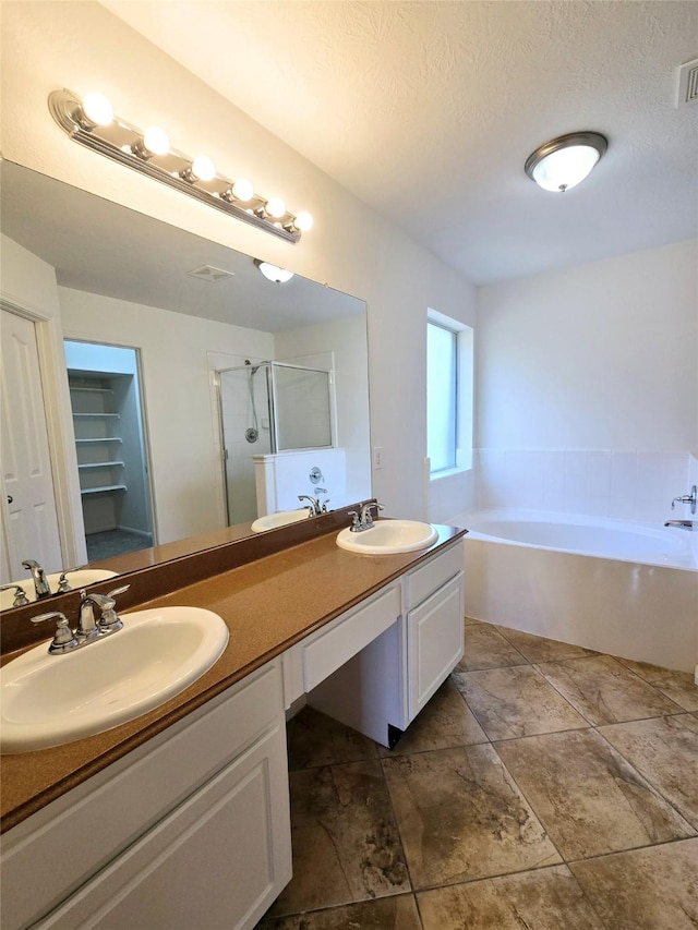 bathroom with vanity, separate shower and tub, and a textured ceiling