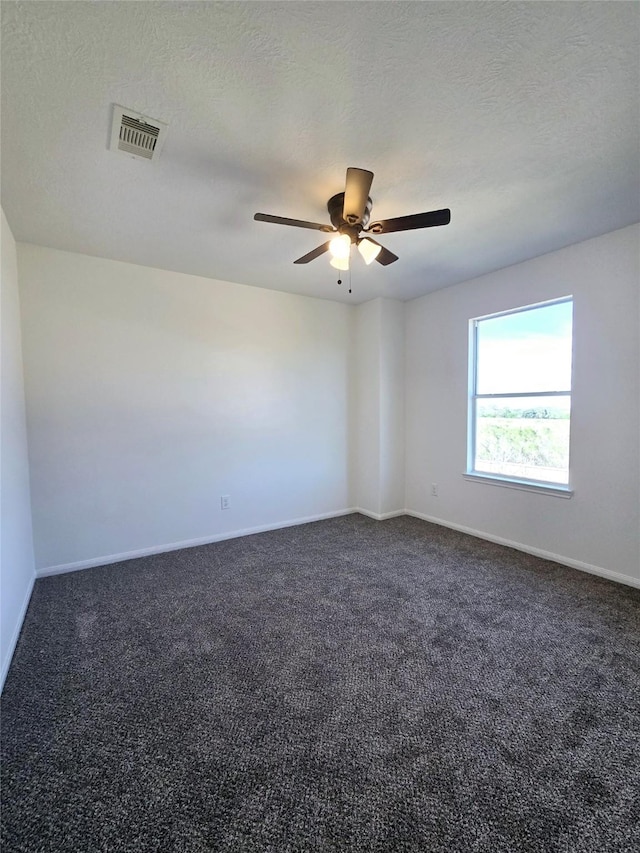 unfurnished room with a textured ceiling, dark carpet, and ceiling fan