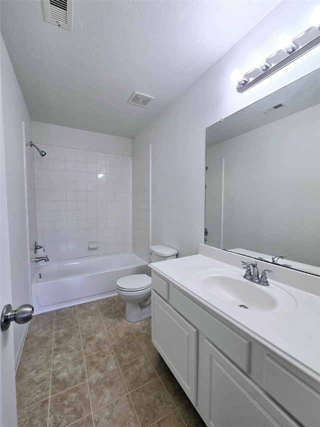 full bathroom featuring vanity, tile patterned floors, tiled shower / bath, toilet, and a textured ceiling