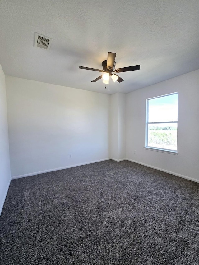 spare room with ceiling fan, dark carpet, and a textured ceiling