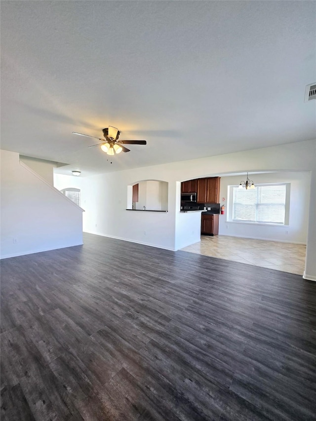 unfurnished living room with dark hardwood / wood-style floors and ceiling fan with notable chandelier