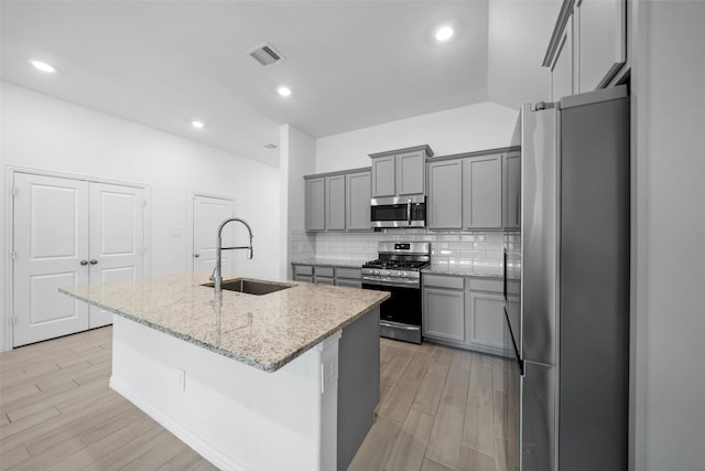 kitchen featuring appliances with stainless steel finishes, an island with sink, light hardwood / wood-style floors, and sink