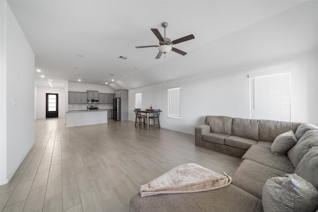 living room featuring light wood-type flooring, vaulted ceiling, and ceiling fan