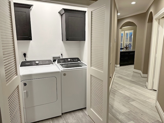 laundry area with light hardwood / wood-style floors, cabinets, and separate washer and dryer