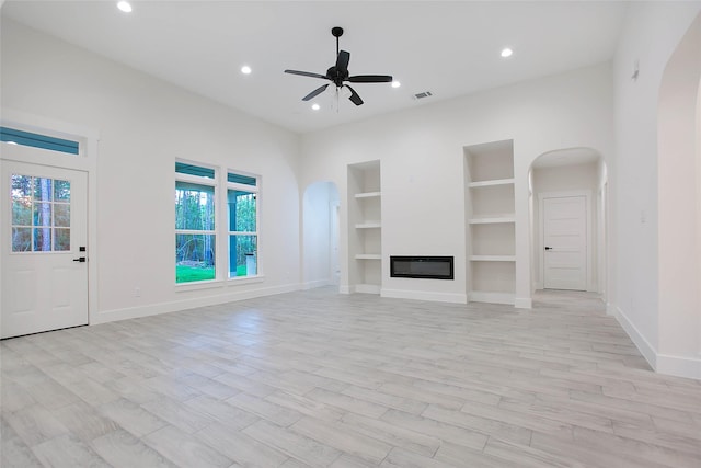 unfurnished living room featuring light wood-type flooring, ceiling fan, and built in features