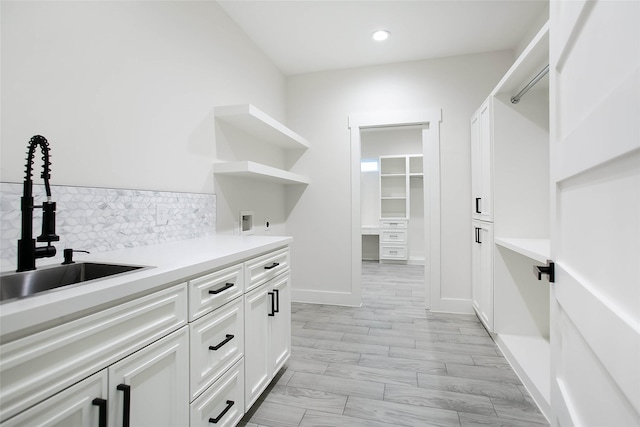 clothes washing area featuring light wood-type flooring, cabinets, hookup for a washing machine, and sink