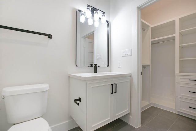 bathroom with toilet, vanity, and tile patterned flooring