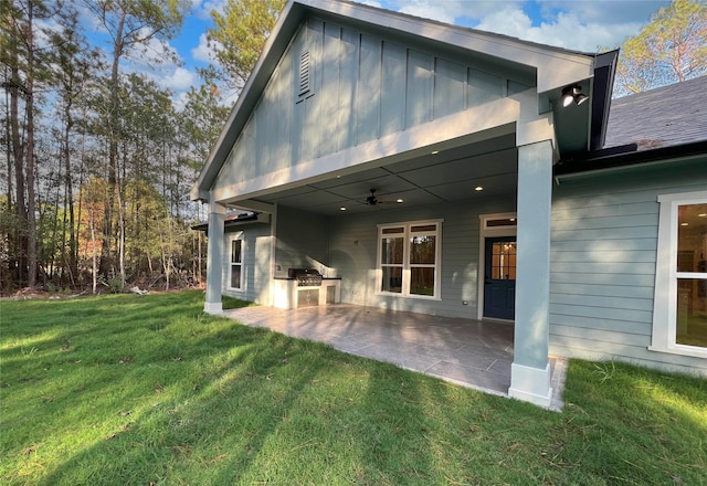 rear view of house with an outdoor kitchen, a lawn, and a patio