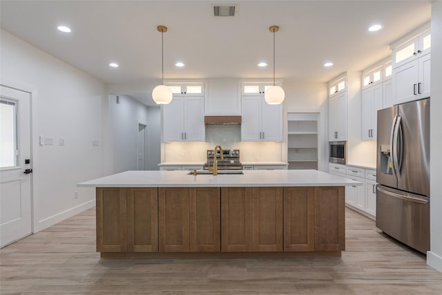 kitchen with white cabinets, stainless steel appliances, and a kitchen island with sink