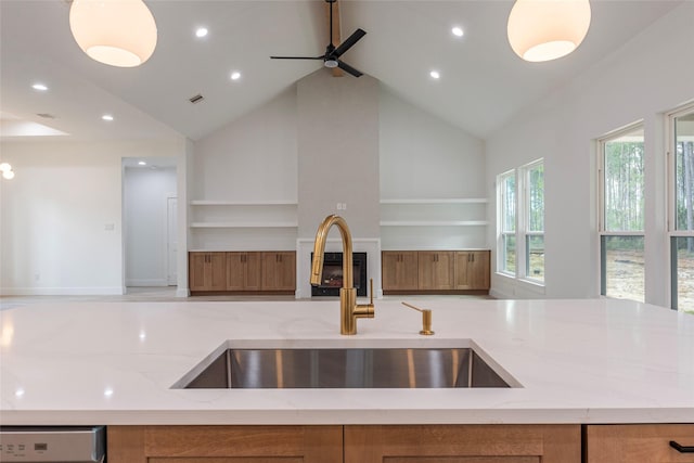 kitchen with light stone countertops, high vaulted ceiling, a wealth of natural light, and sink