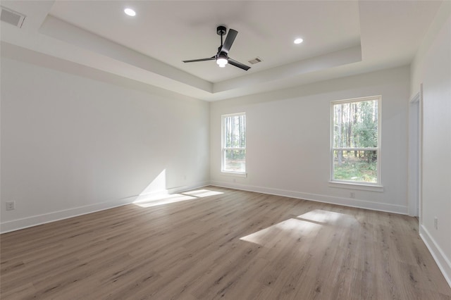 spare room with ceiling fan, a raised ceiling, and light hardwood / wood-style flooring