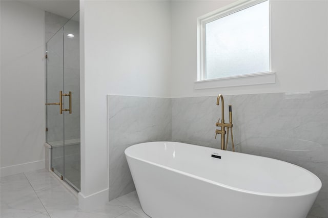 bathroom featuring shower with separate bathtub and tile walls