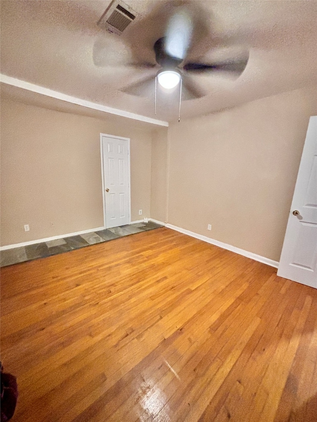 empty room with a textured ceiling, hardwood / wood-style flooring, and ceiling fan