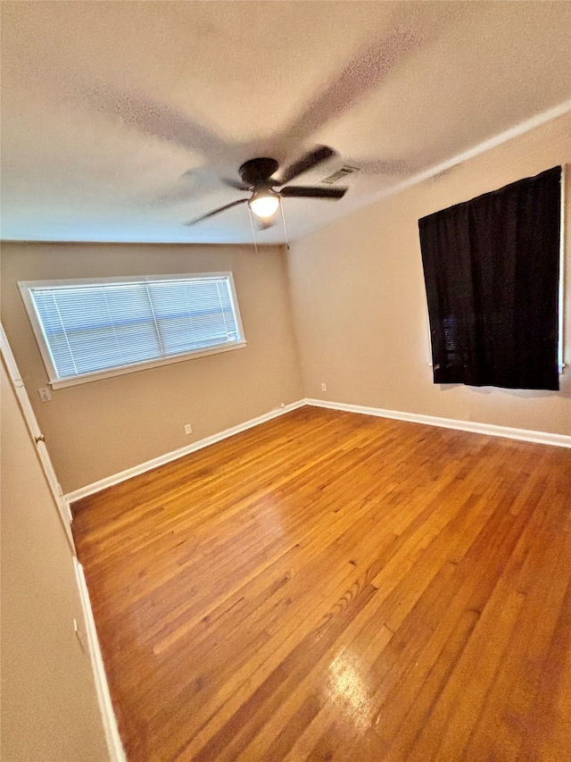 empty room with ceiling fan, a textured ceiling, and light hardwood / wood-style flooring