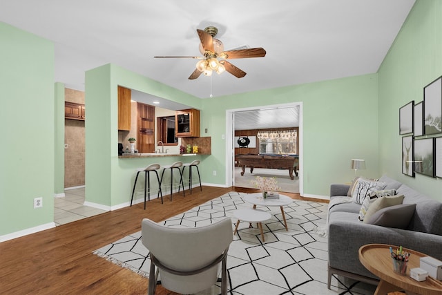 living room with ceiling fan, light wood-type flooring, sink, and pool table