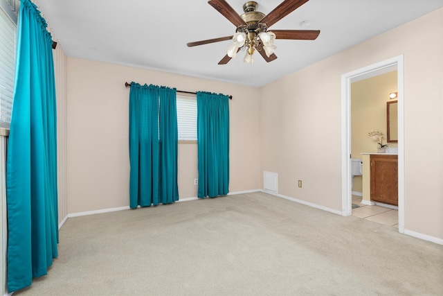 unfurnished bedroom with ceiling fan, light colored carpet, and ensuite bath