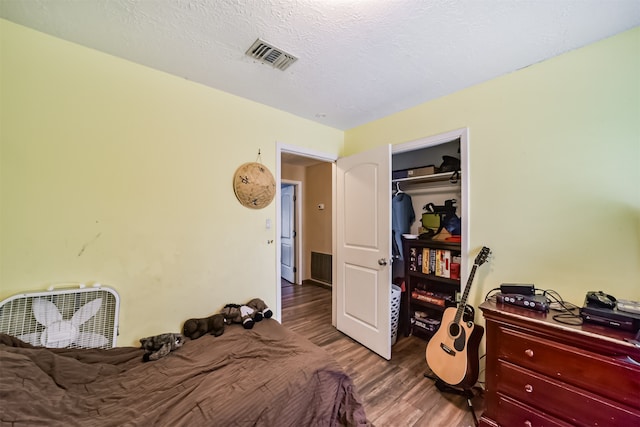 bedroom with wood-type flooring, a textured ceiling, and a closet