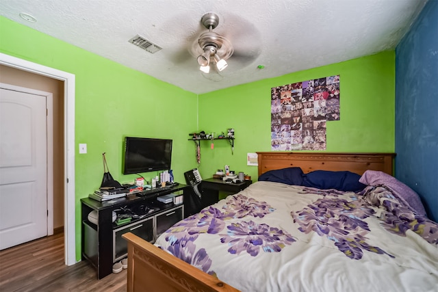 bedroom featuring hardwood / wood-style floors, a textured ceiling, and ceiling fan