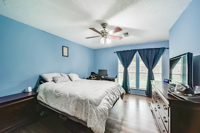 bedroom featuring a ceiling fan, visible vents, light wood-style flooring, and a textured ceiling