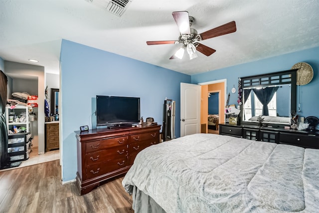 bedroom with visible vents, a ceiling fan, a textured ceiling, wood finished floors, and baseboards