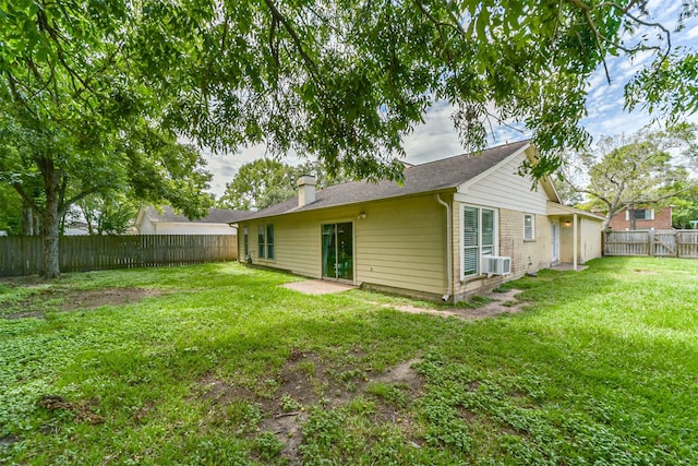 back of house featuring a fenced backyard, a chimney, and a lawn