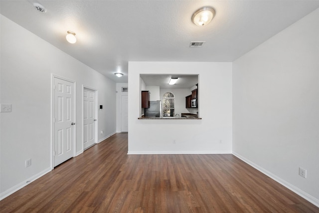 unfurnished living room featuring dark hardwood / wood-style flooring and a textured ceiling