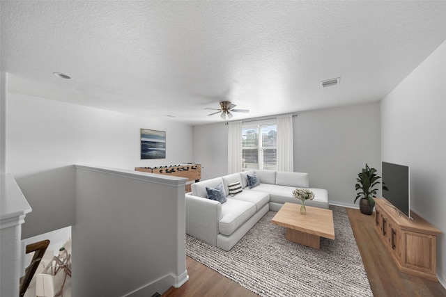 living room with hardwood / wood-style flooring, ceiling fan, and a textured ceiling