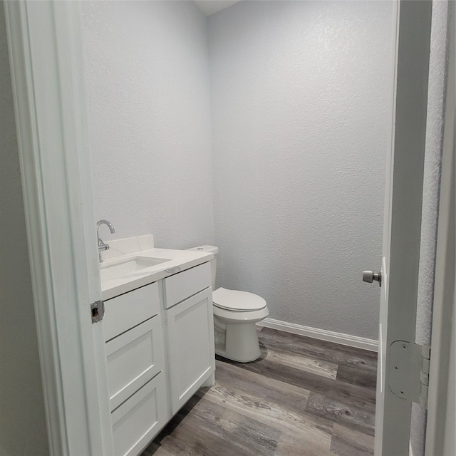 bathroom with toilet, vanity, and hardwood / wood-style flooring