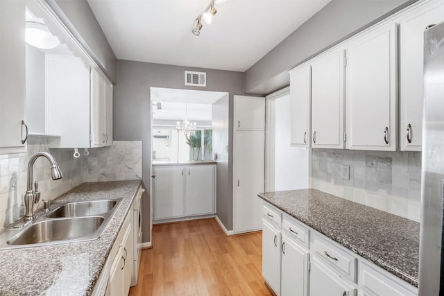 kitchen with white cabinets, decorative backsplash, light hardwood / wood-style floors, and sink