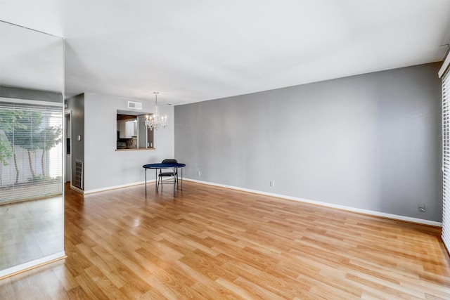 unfurnished living room featuring light hardwood / wood-style floors and an inviting chandelier