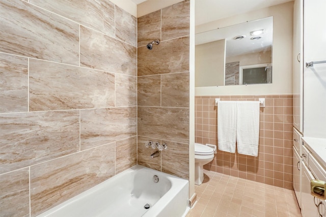 full bathroom with tiled shower / bath combo, tile patterned floors, toilet, vanity, and tile walls