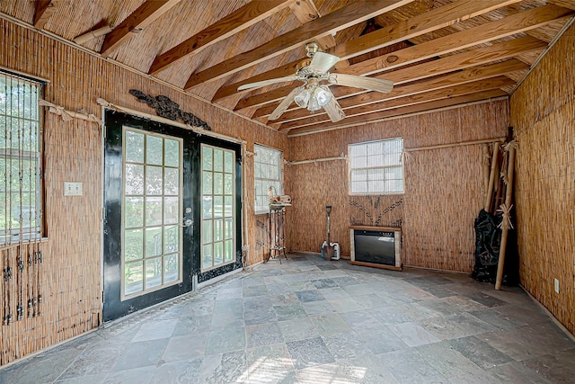 interior space featuring ceiling fan, vaulted ceiling with beams, and wooden walls